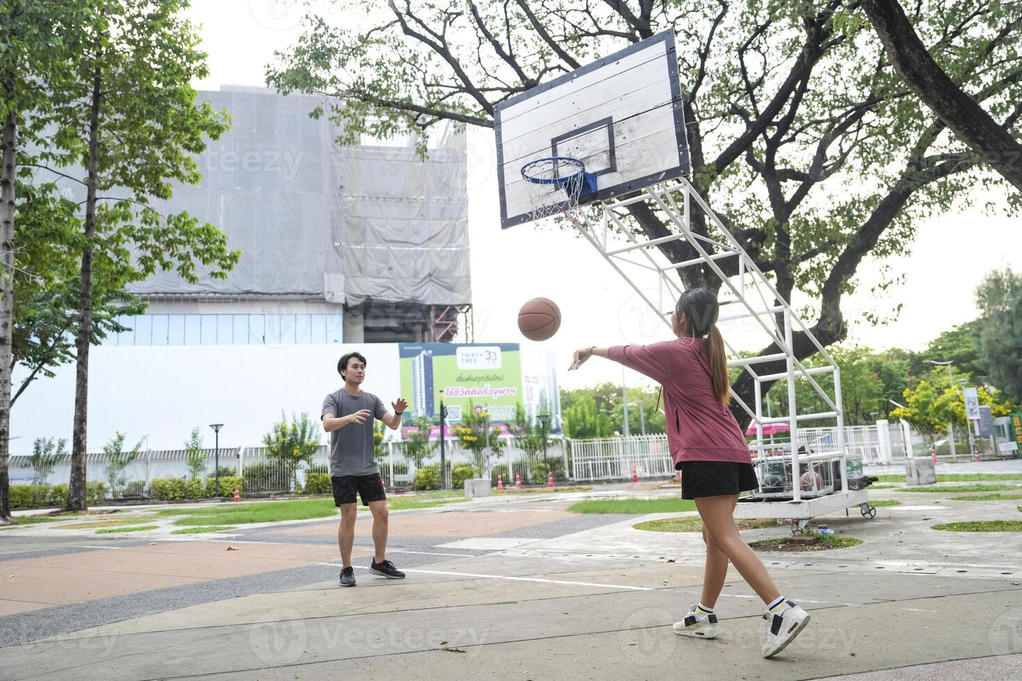The male and female basketball players practice using the ball in the park court diligently and happily. photo