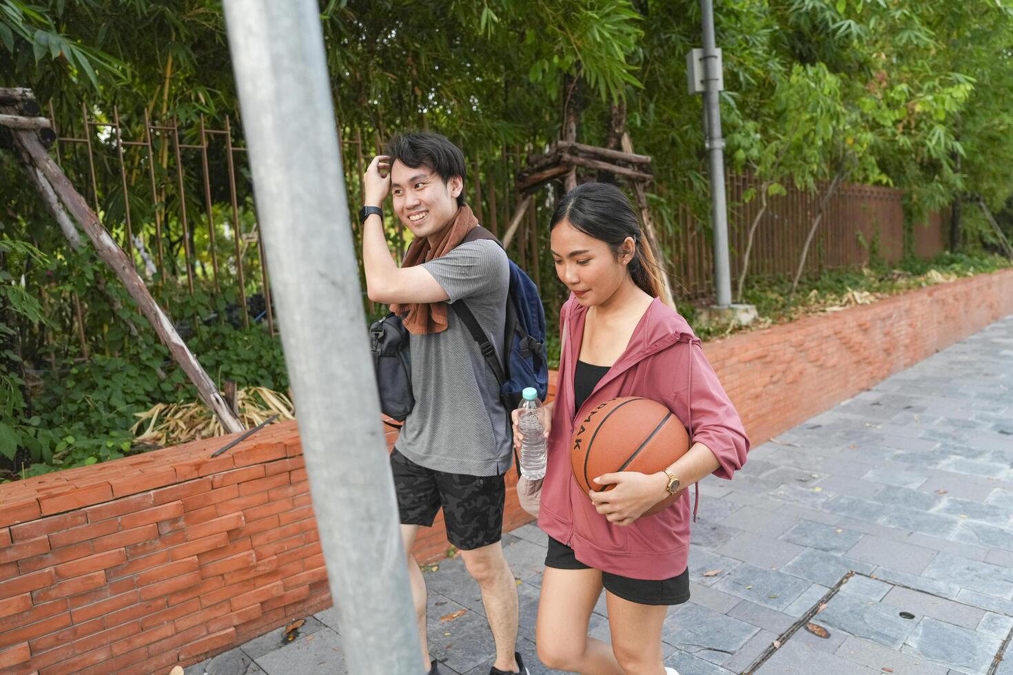 The male and female basketball players practice using the ball in the park court diligently and happily. photo