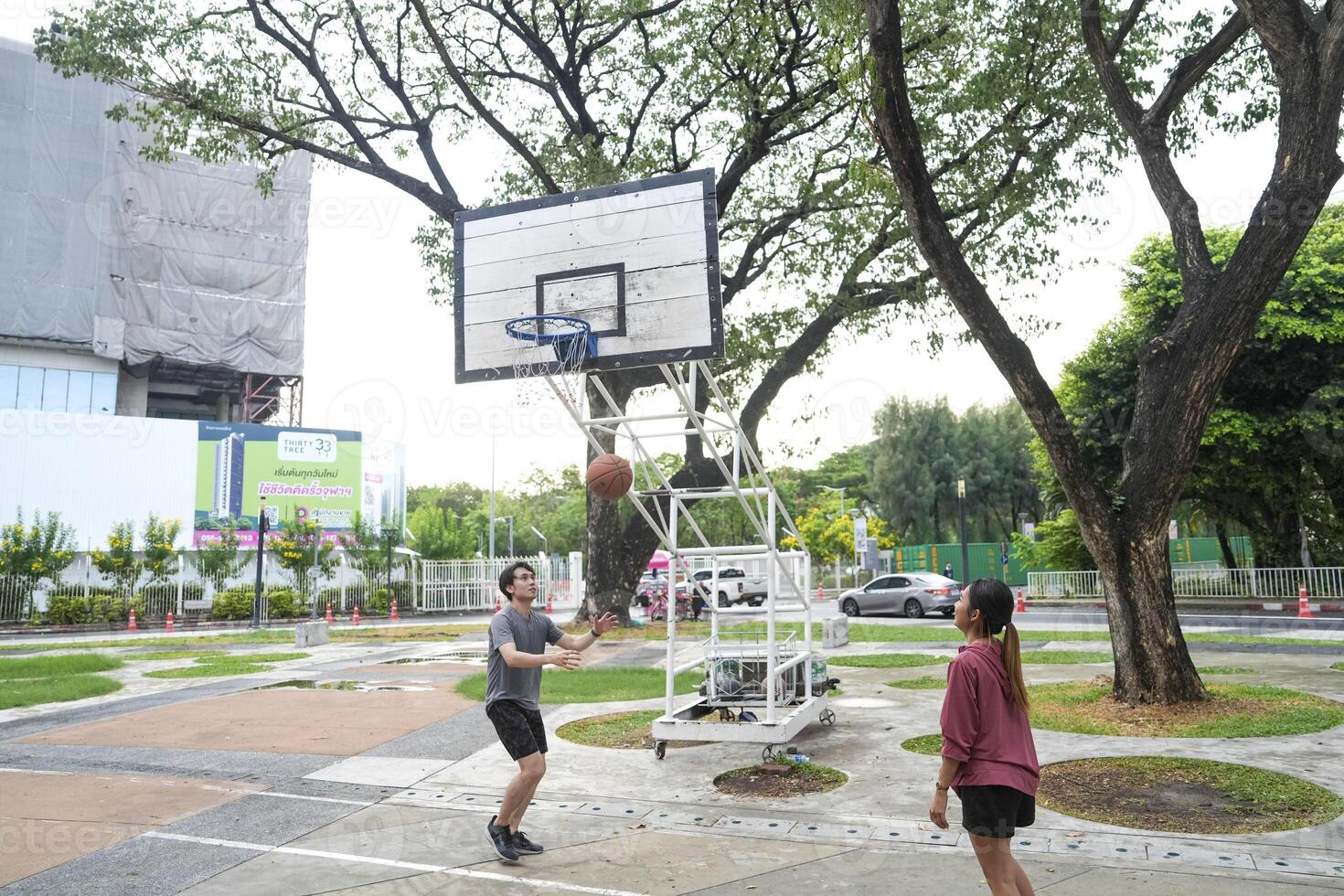 The male and female basketball players practice using the ball in the park court diligently and happily. photo