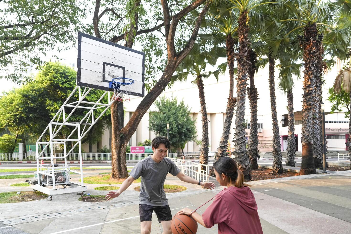 The male and female basketball players practice using the ball in the park court diligently and happily. photo