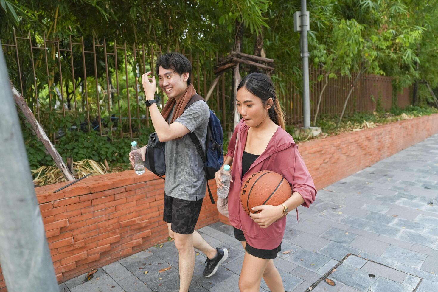 The male and female basketball players practice using the ball in the park court diligently and happily. photo