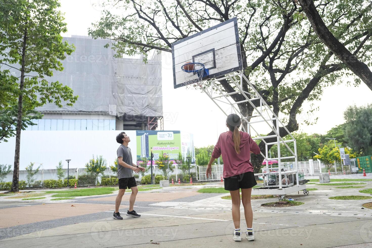 The male and female basketball players practice using the ball in the park court diligently and happily. photo