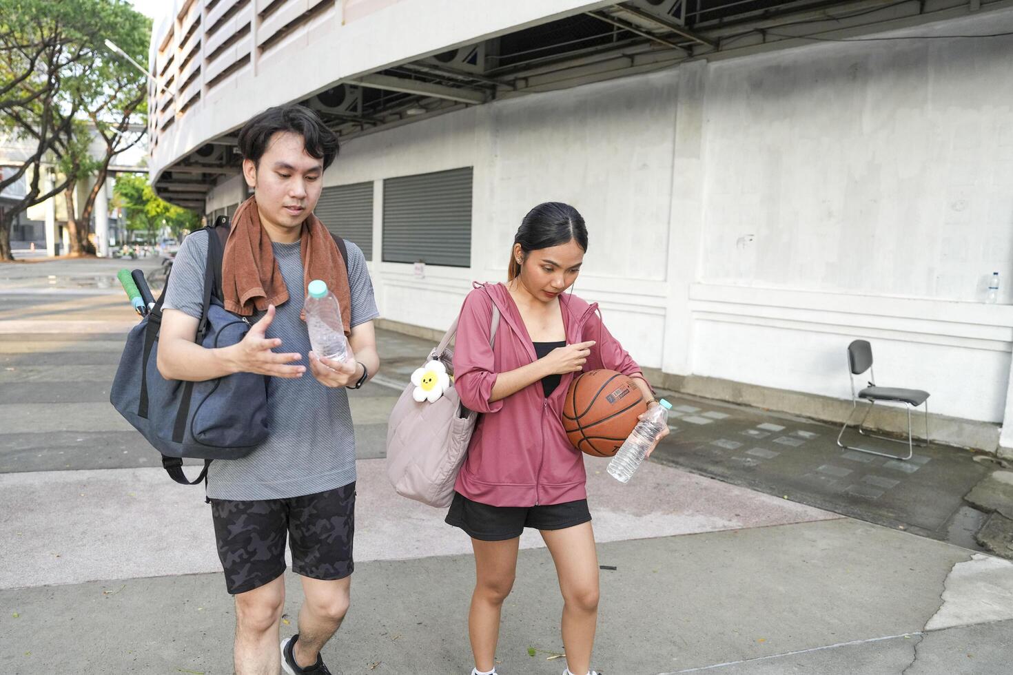 The male and female basketball players practice using the ball in the park court diligently and happily. photo