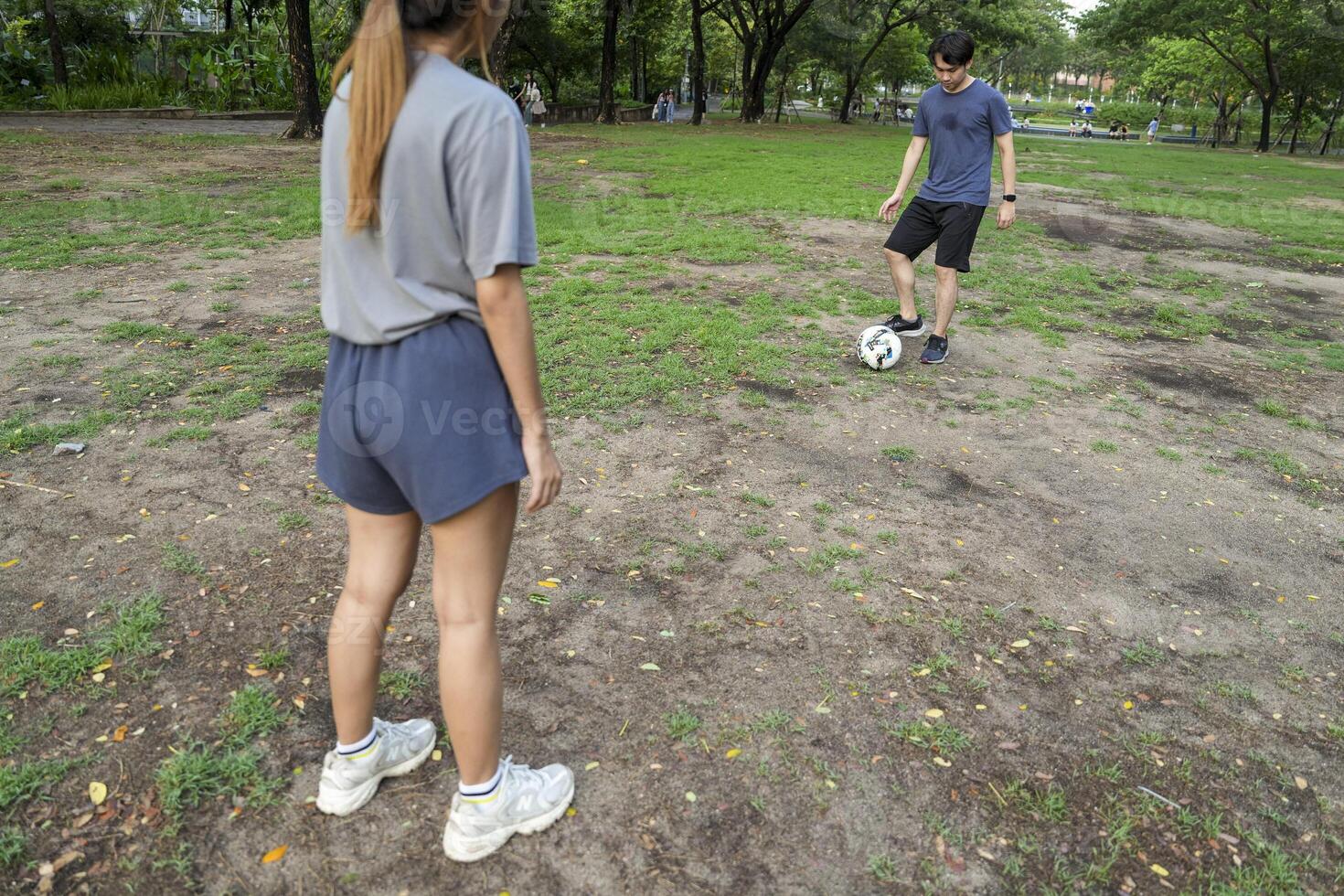Asian man and woman are kicking and warming up before playing in soccer at outdoor park. photo