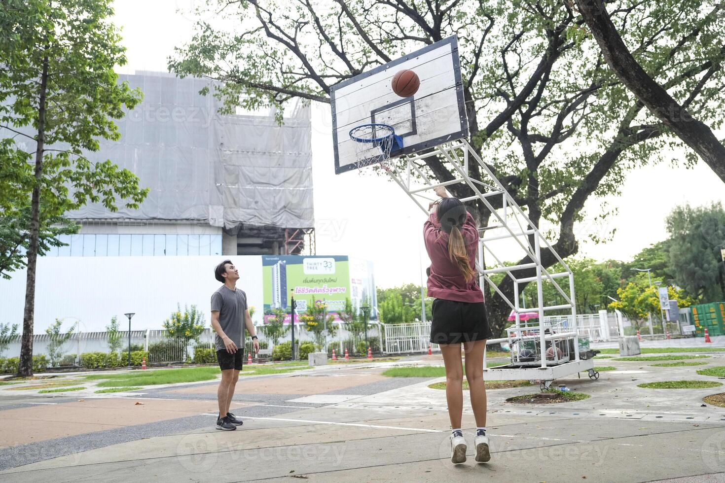 The male and female basketball players practice using the ball in the park court diligently and happily. photo