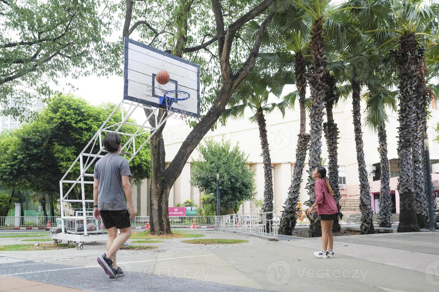 The male and female basketball players practice using the ball in the park court diligently and happily. photo