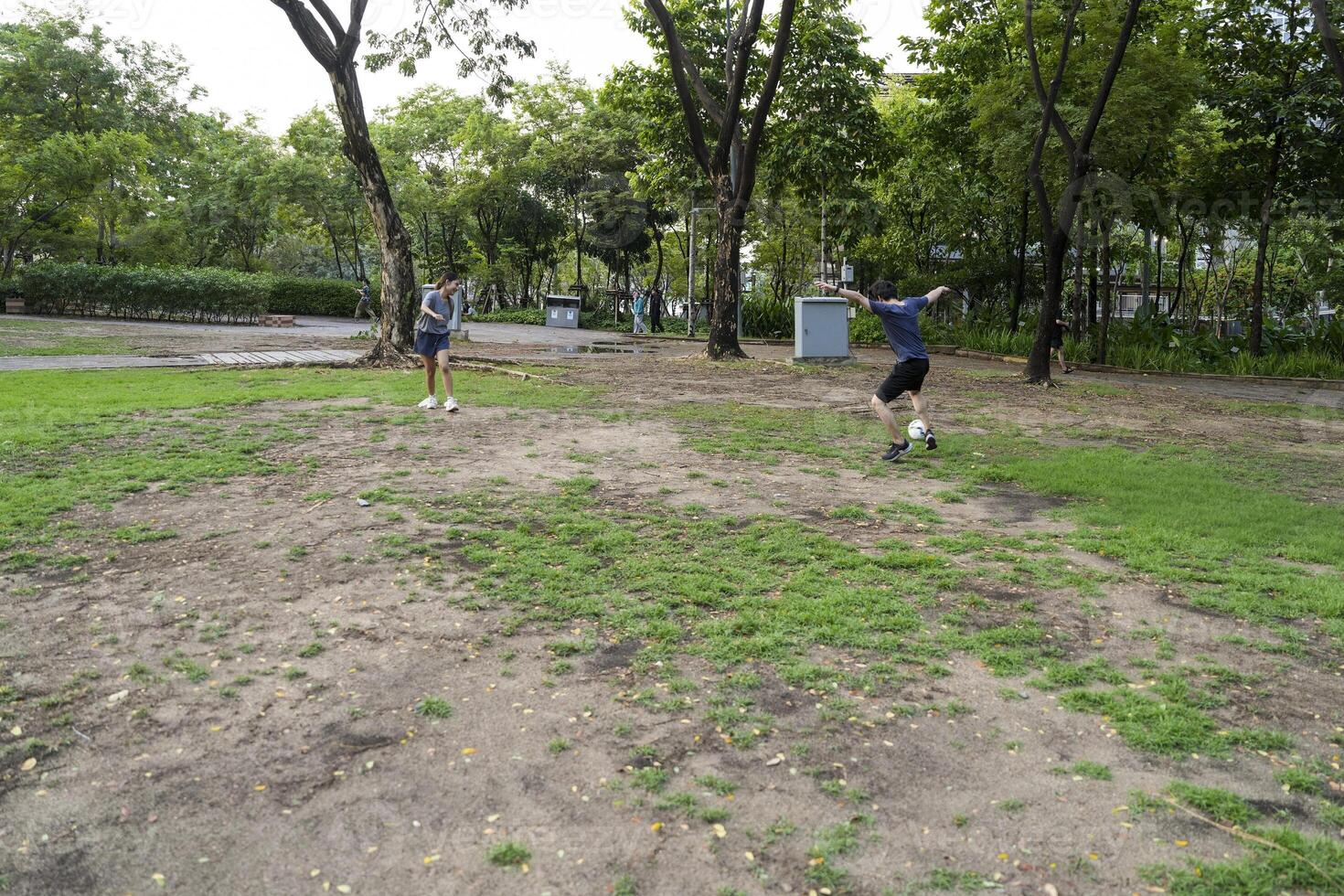 Asian man and woman are kicking and warming up before playing in soccer at outdoor park. photo