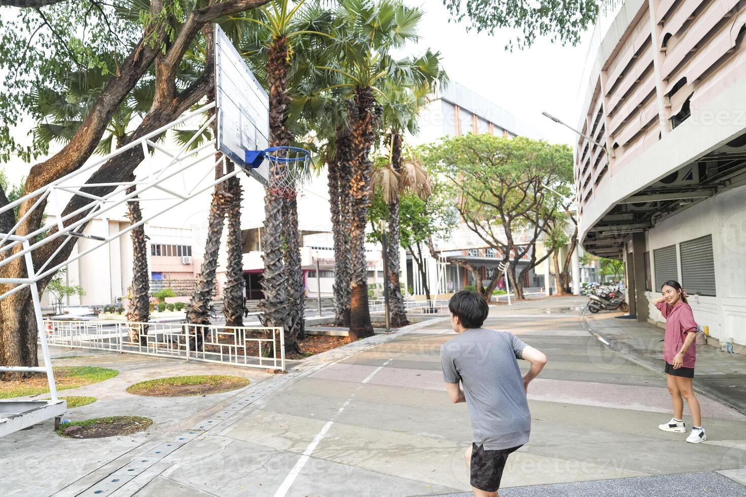 The male and female basketball players practice using the ball in the park court diligently and happily. photo