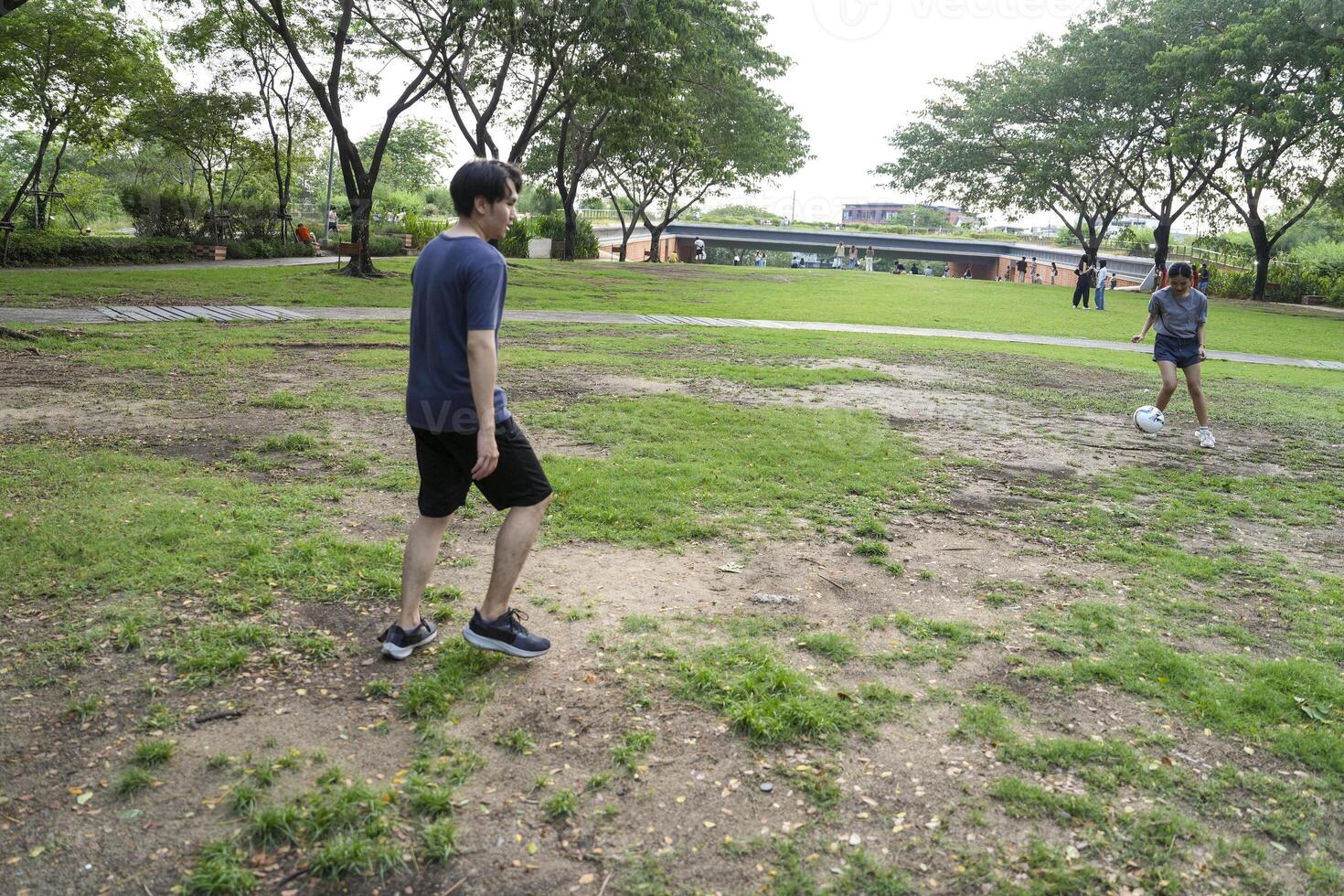 Asian man and woman are kicking and warming up before playing in soccer at outdoor park. photo