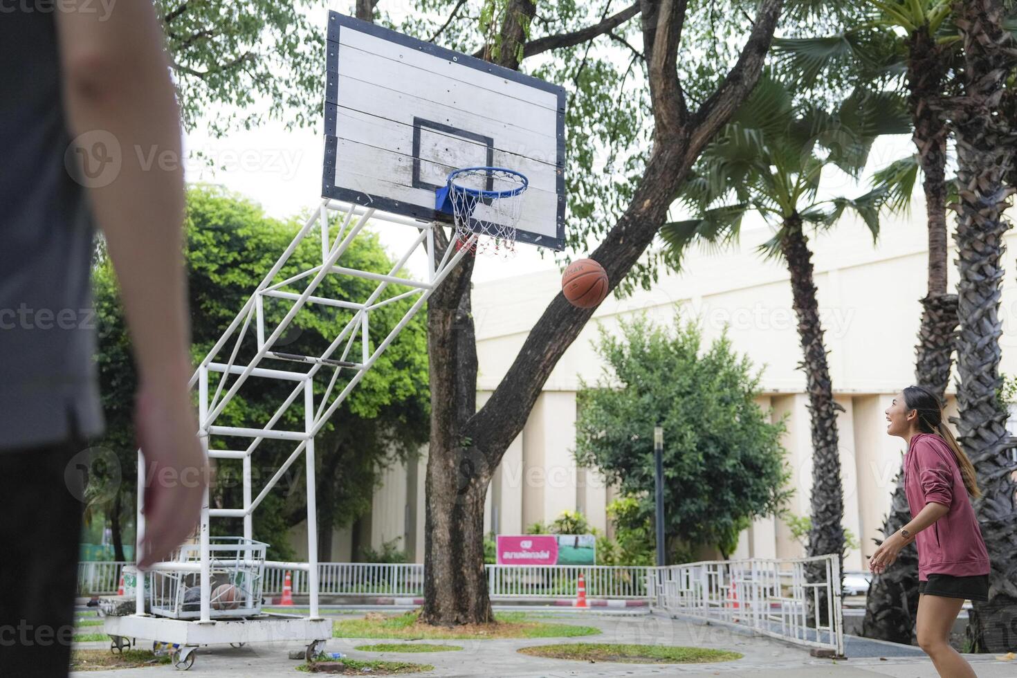 The male and female basketball players practice using the ball in the park court diligently and happily. photo