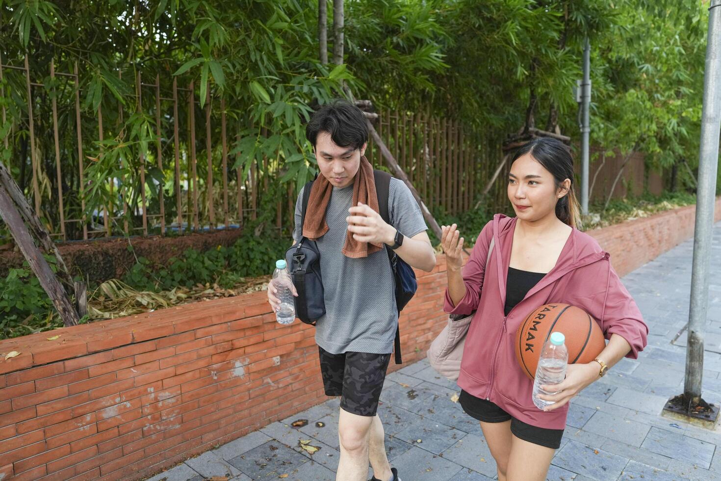 The male and female basketball players practice using the ball in the park court diligently and happily. photo