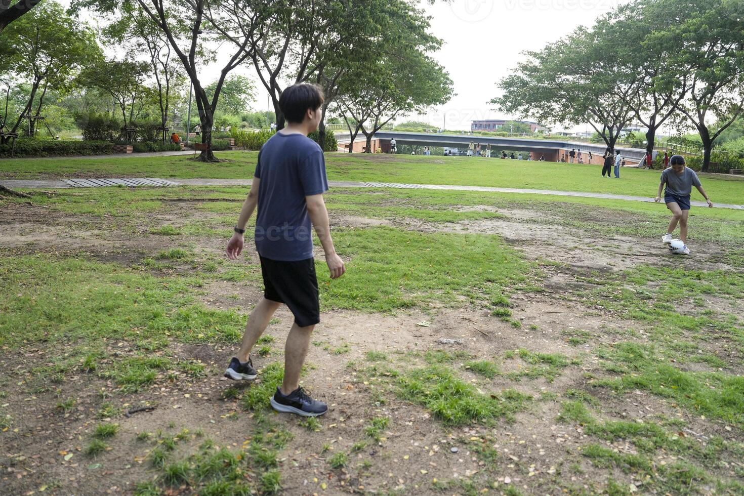 Asian man and woman are kicking and warming up before playing in soccer at outdoor park. photo