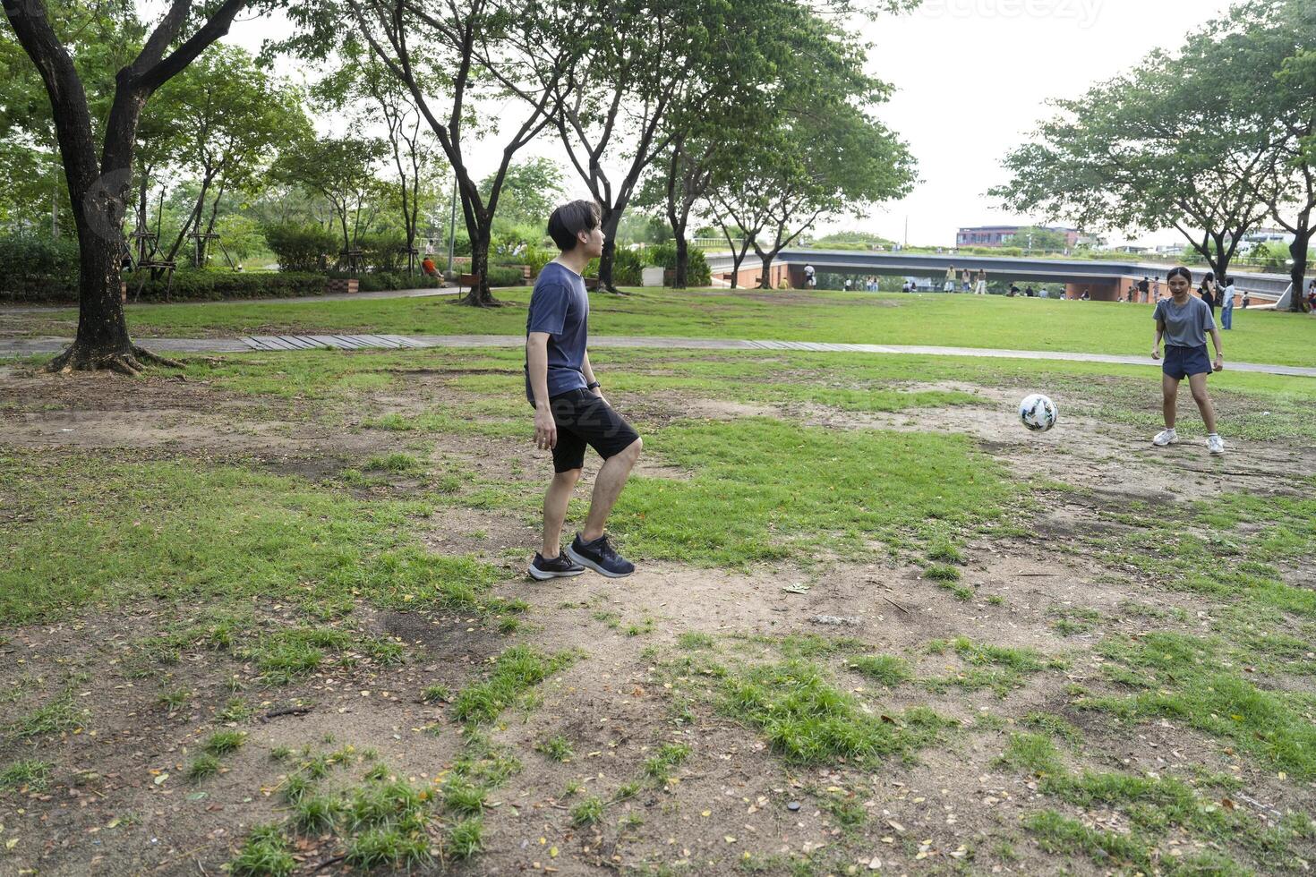Asian man and woman are kicking and warming up before playing in soccer at outdoor park. photo