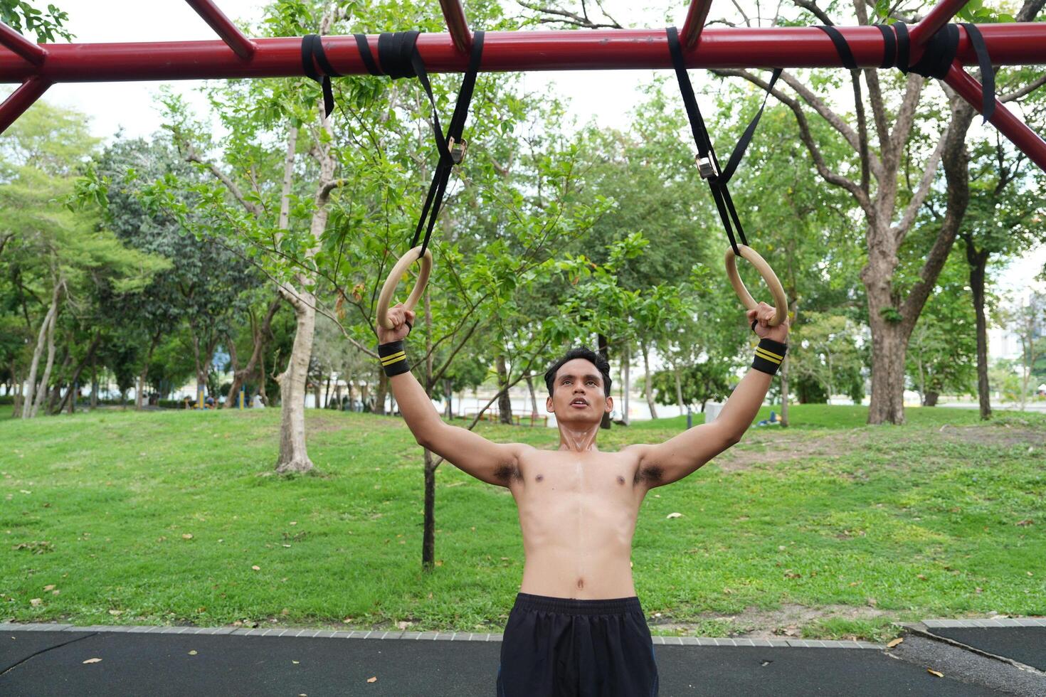 Asian man practicing gymnastics, doing gymnastics bar and hoop exercises and stretching, resting for sports. photo