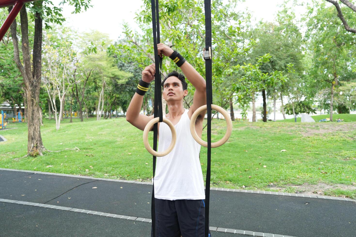 Asian man practicing gymnastics doing gymnastics bar and hoop exercises and stretching and resting for sports. photo