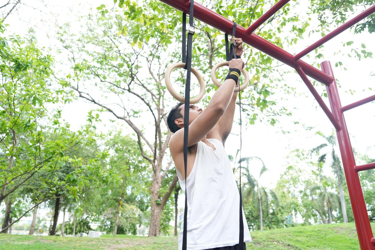 Asian man practicing gymnastics doing gymnastics bar and hoop exercises and stretching and resting for sports. photo