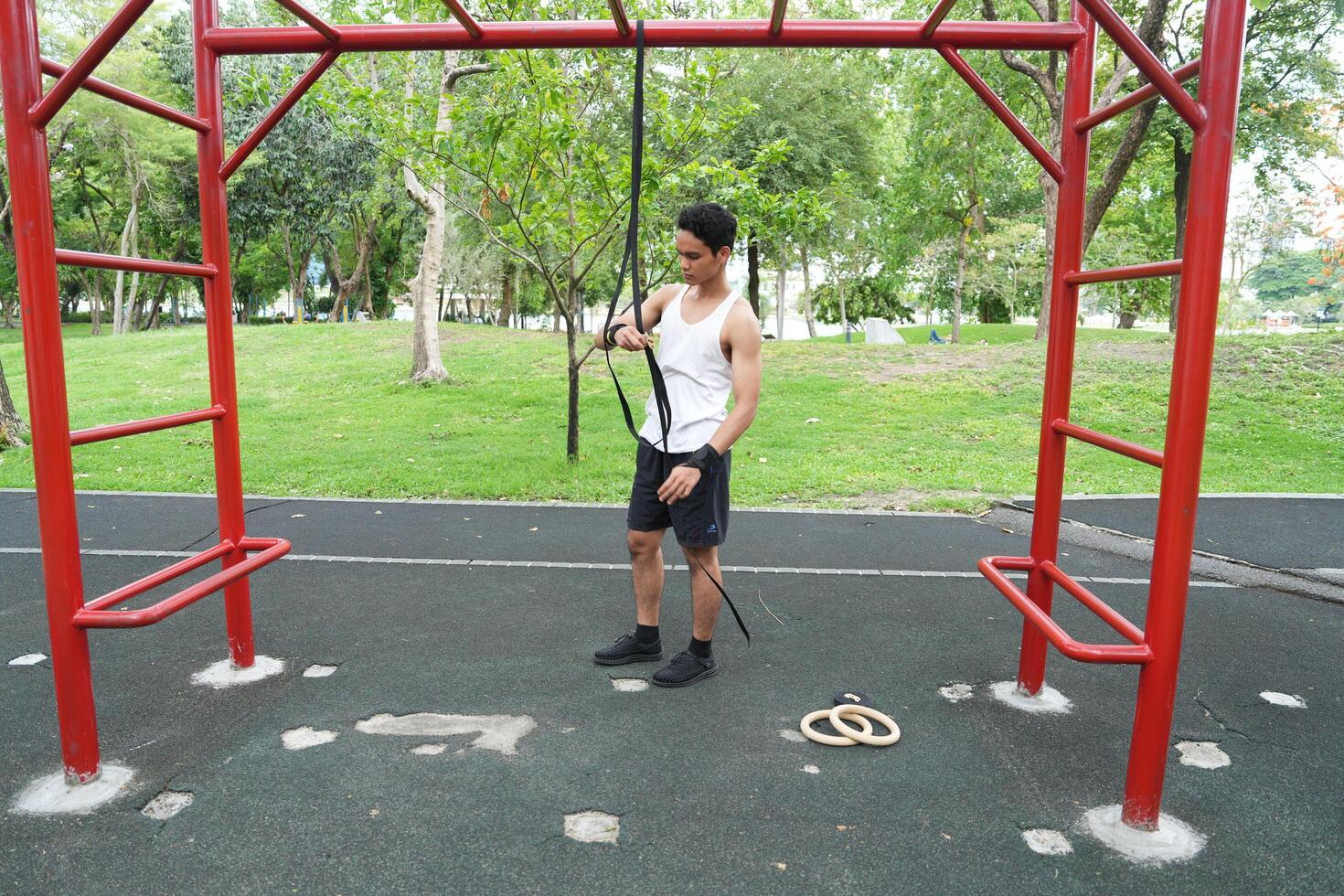 Asian man practicing gymnastics doing gymnastics bar and hoop exercises and stretching and resting for sports. photo