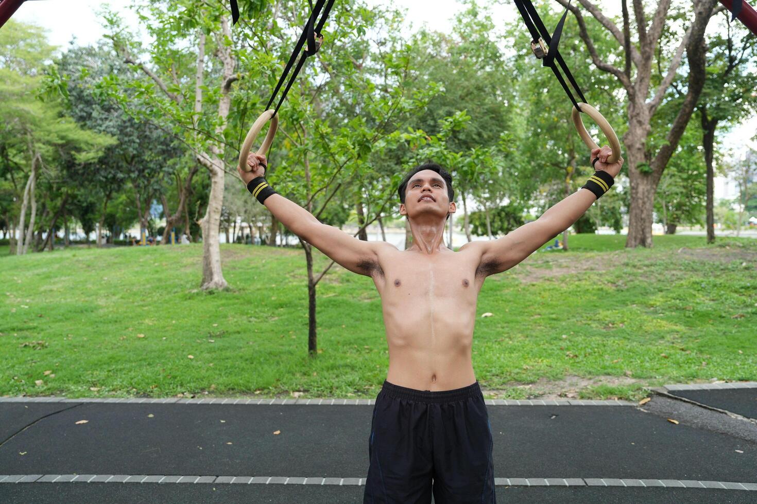 Asian man practicing gymnastics, doing gymnastics bar and hoop exercises and stretching, resting for sports. photo