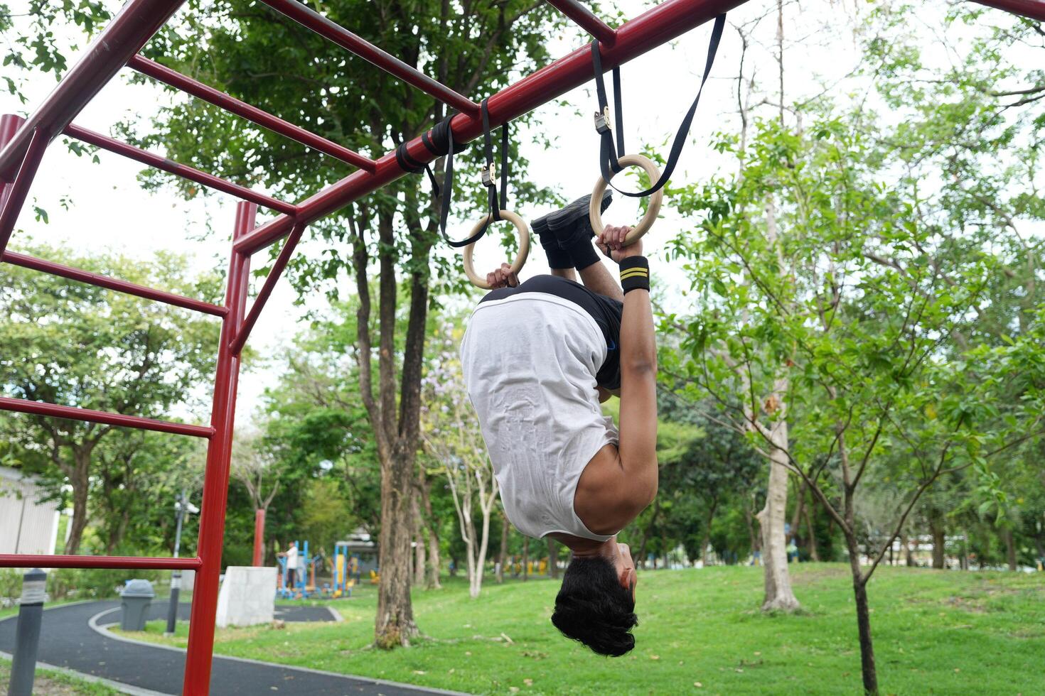 Asian man practicing gymnastics, doing gymnastics bar and hoop exercises and stretching, resting for sports. photo