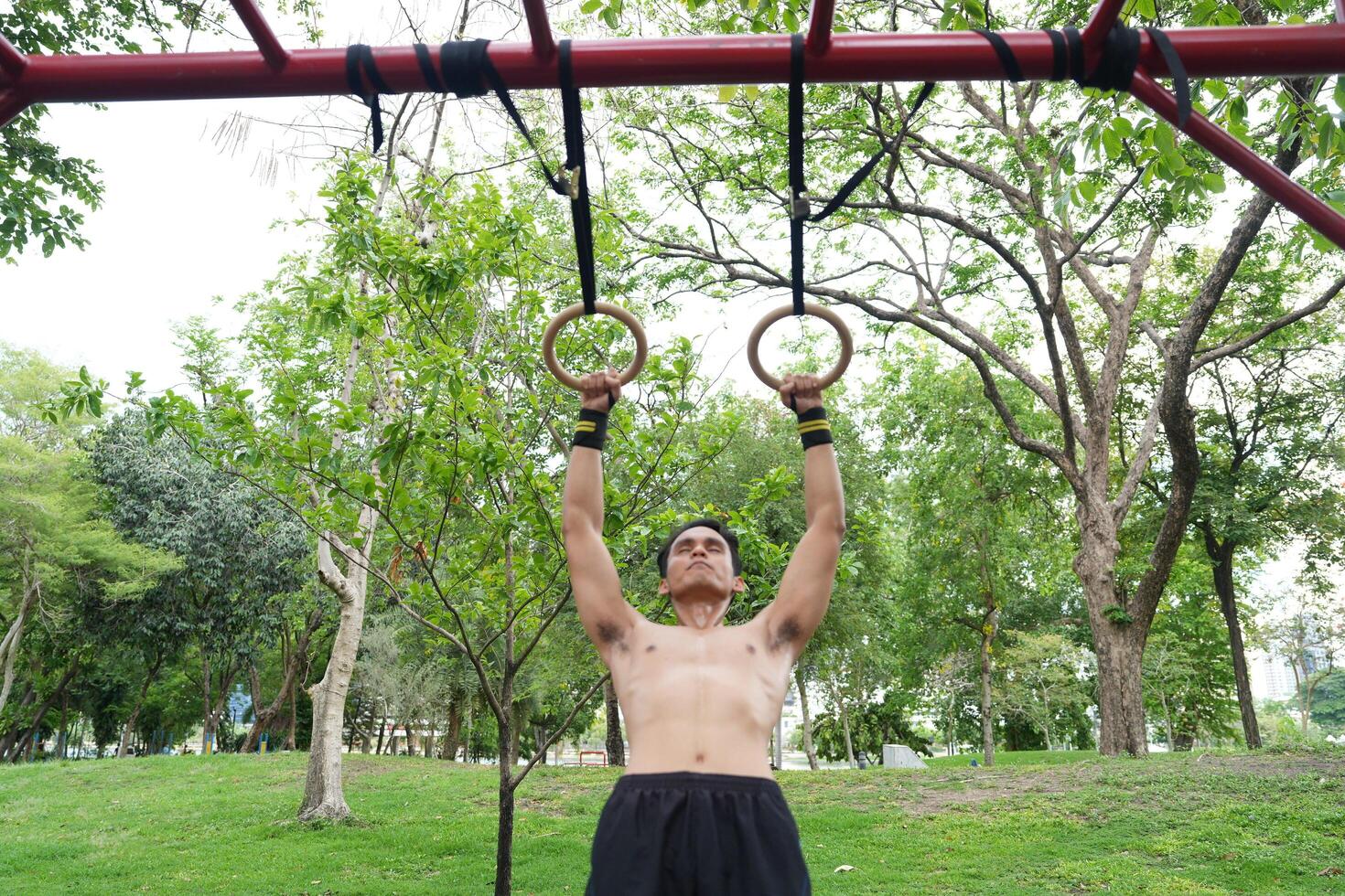 Asian man practicing gymnastics, doing gymnastics bar and hoop exercises and stretching, resting for sports. photo