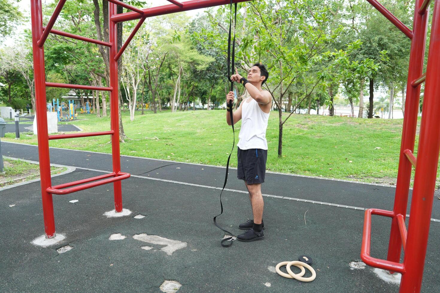 Asian man practicing gymnastics doing gymnastics bar and hoop exercises and stretching and resting for sports. photo