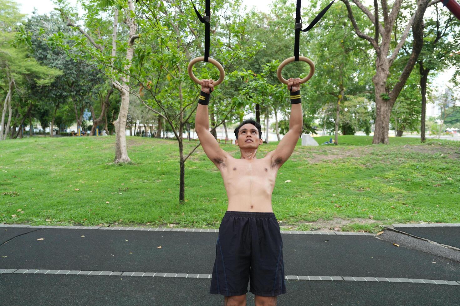 Asian man practicing gymnastics, doing gymnastics bar and hoop exercises and stretching, resting for sports. photo