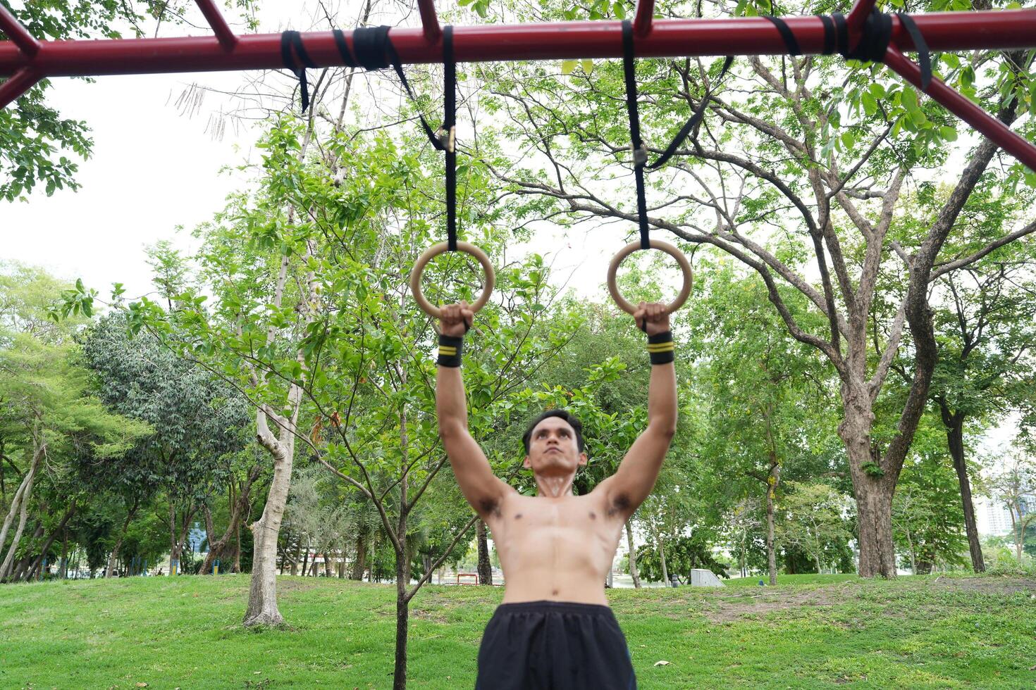 Asian man practicing gymnastics, doing gymnastics bar and hoop exercises and stretching, resting for sports. photo