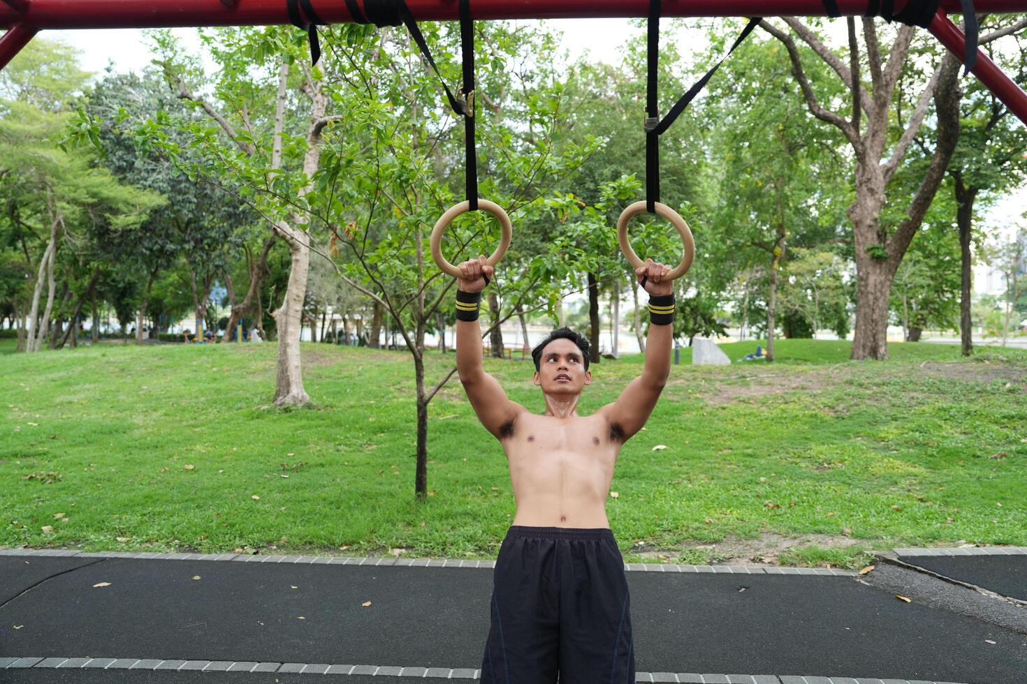 Asian man practicing gymnastics, doing gymnastics bar and hoop exercises and stretching, resting for sports. photo