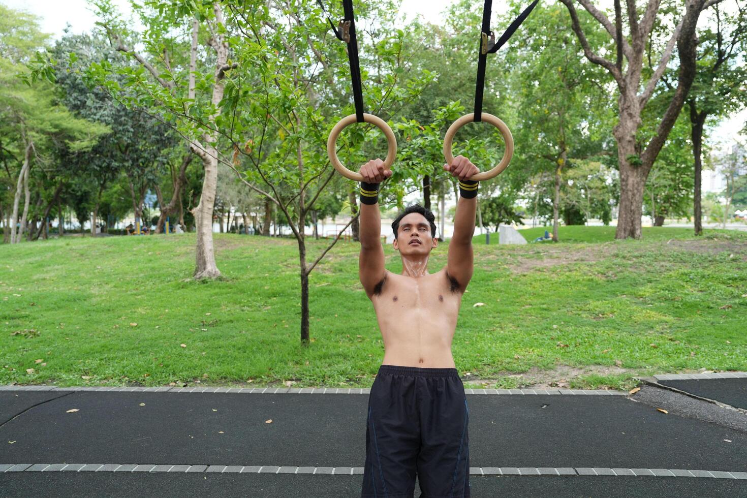 Asian man practicing gymnastics, doing gymnastics bar and hoop exercises and stretching, resting for sports. photo