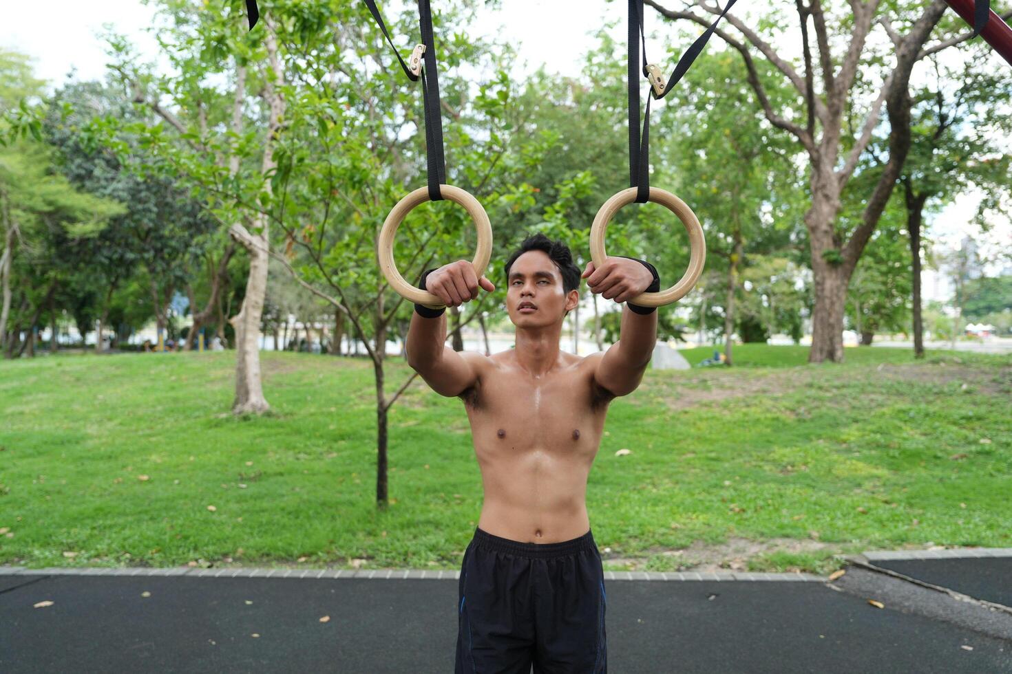 Asian man practicing gymnastics, doing gymnastics bar and hoop exercises and stretching, resting for sports. photo