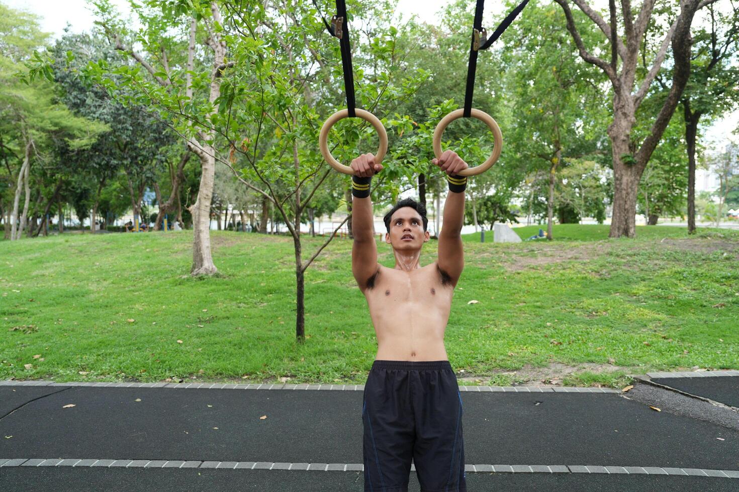 Asian man practicing gymnastics, doing gymnastics bar and hoop exercises and stretching, resting for sports. photo