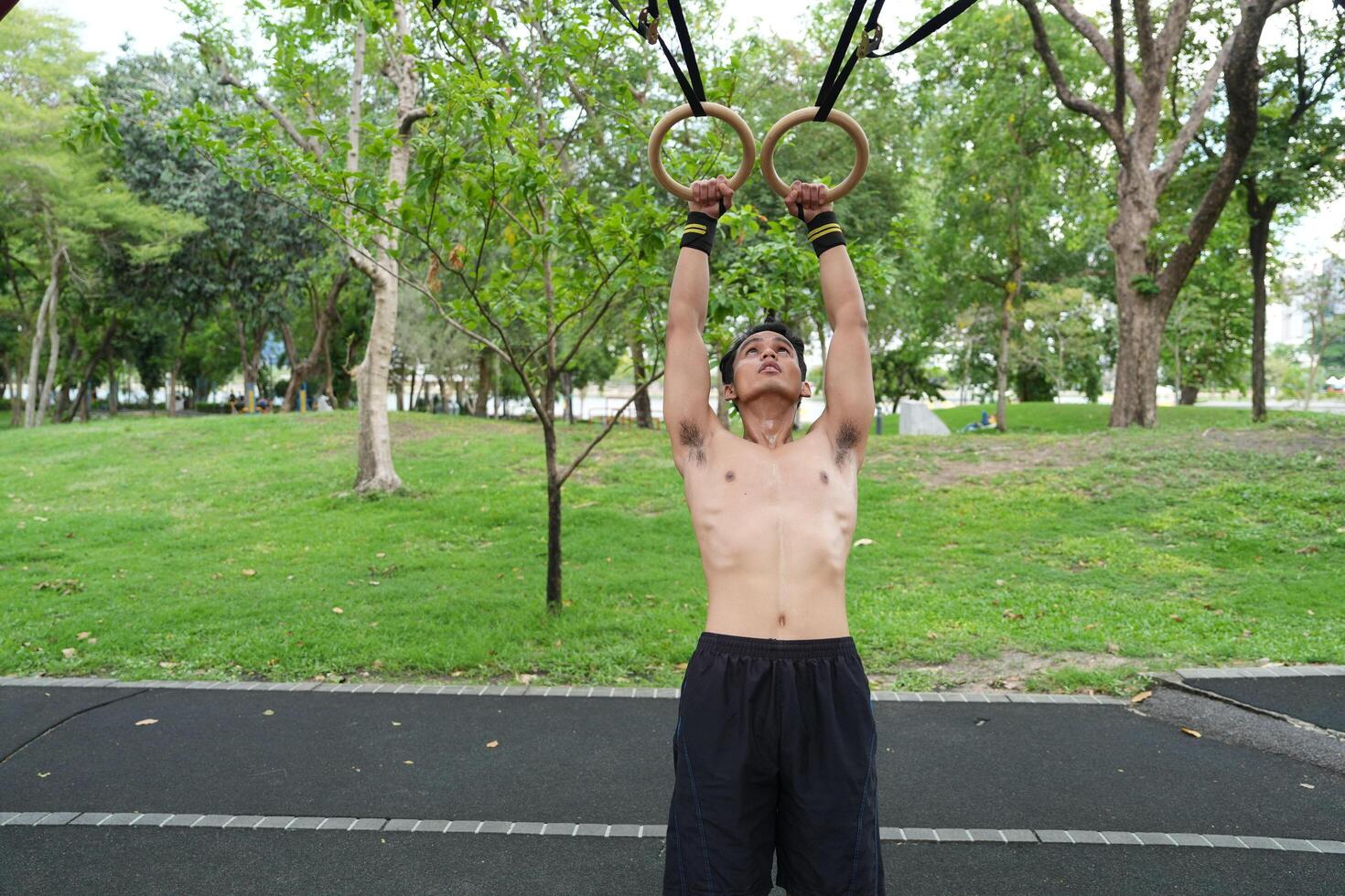 Asian man practicing gymnastics, doing gymnastics bar and hoop exercises and stretching, resting for sports. photo