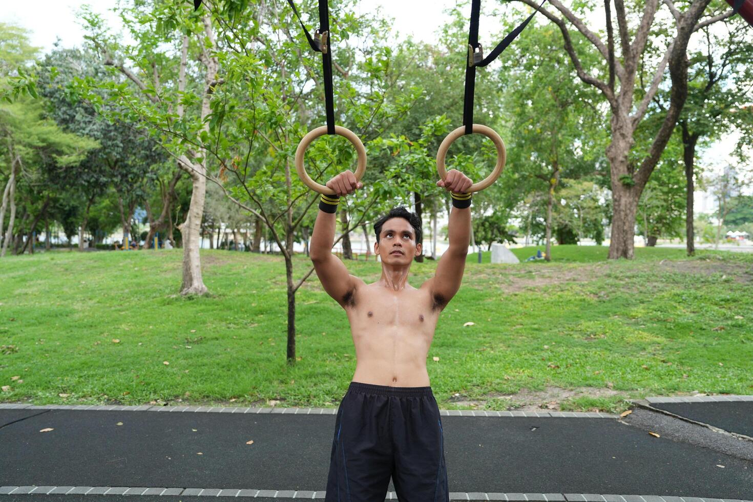 Asian man practicing gymnastics, doing gymnastics bar and hoop exercises and stretching, resting for sports. photo
