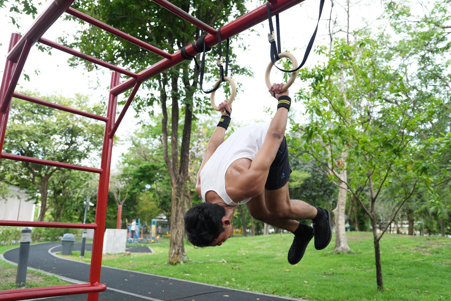 Asian man practicing gymnastics, doing gymnastics bar and hoop exercises and stretching, resting for sports. photo