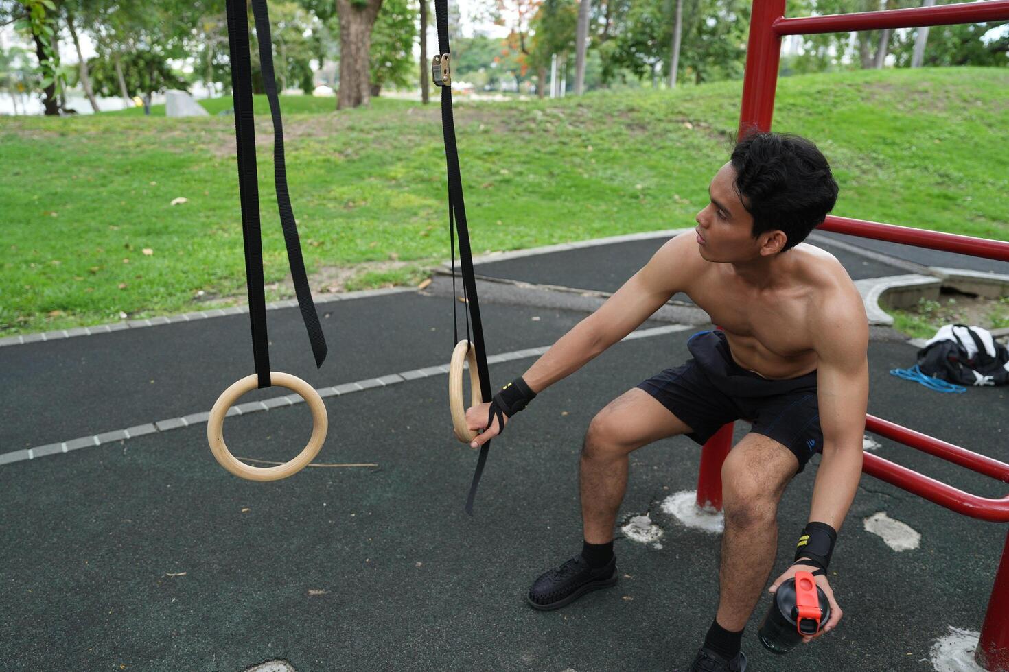 Asian man practicing gymnastics, doing gymnastics bar and hoop exercises and stretching, resting for sports. photo