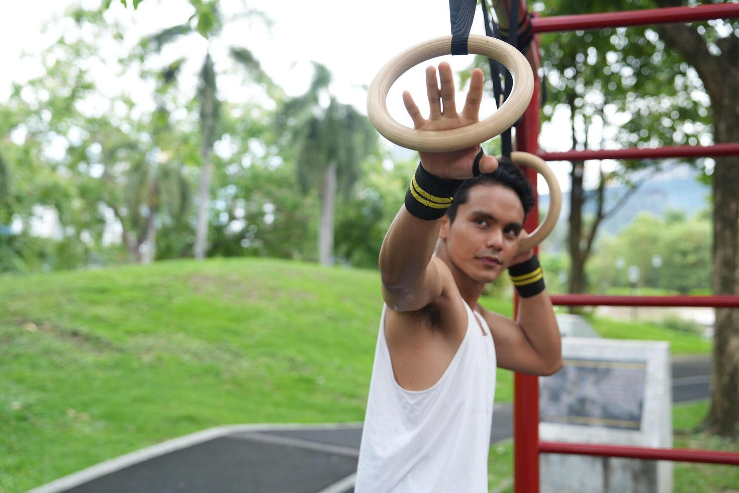 Asian man practicing gymnastics, doing gymnastics bar and hoop exercises and stretching, resting for sports. photo