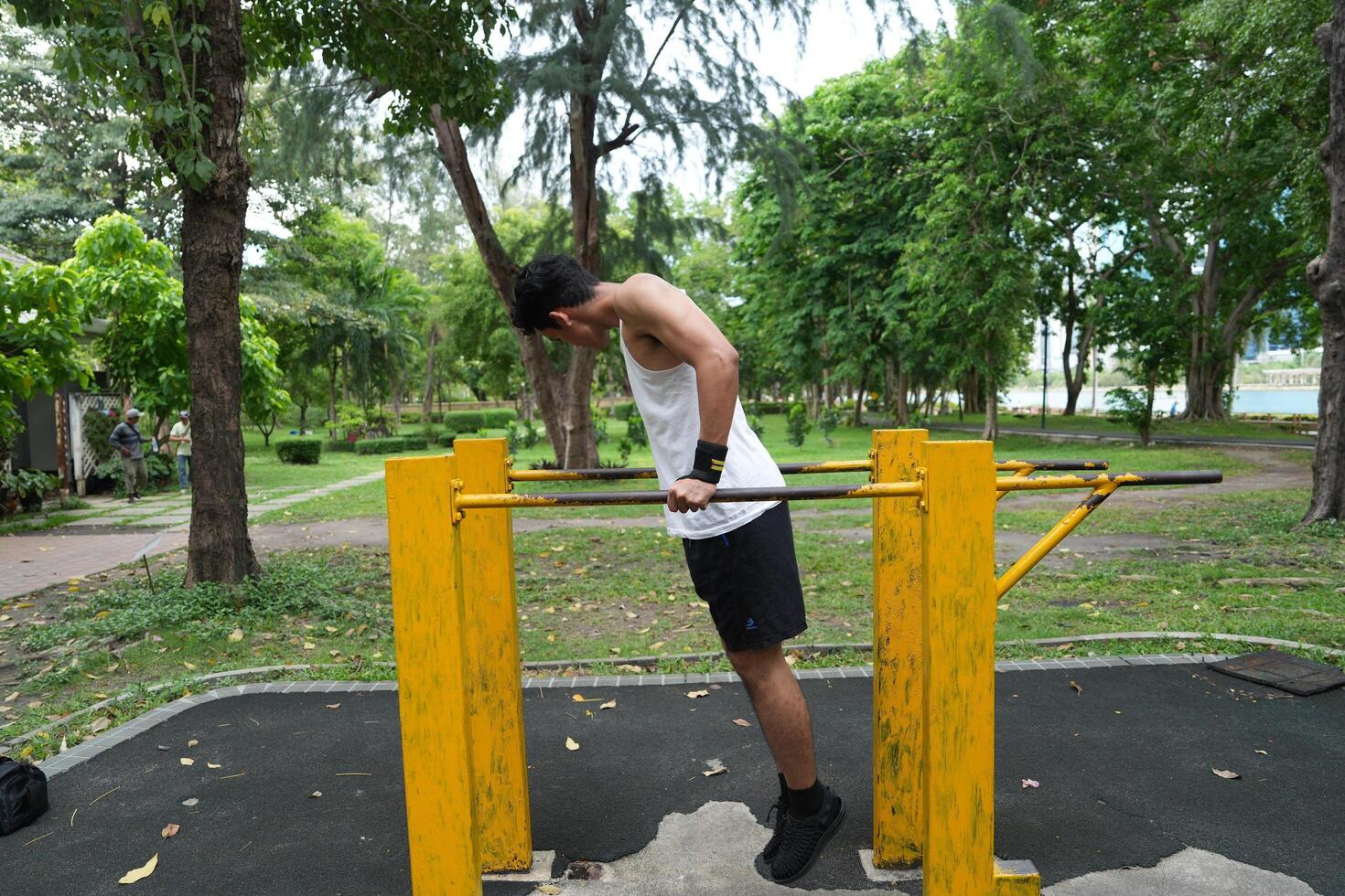 Asian man practicing gymnastics, doing gymnastics bar and hoop exercises and stretching, resting for sports. photo
