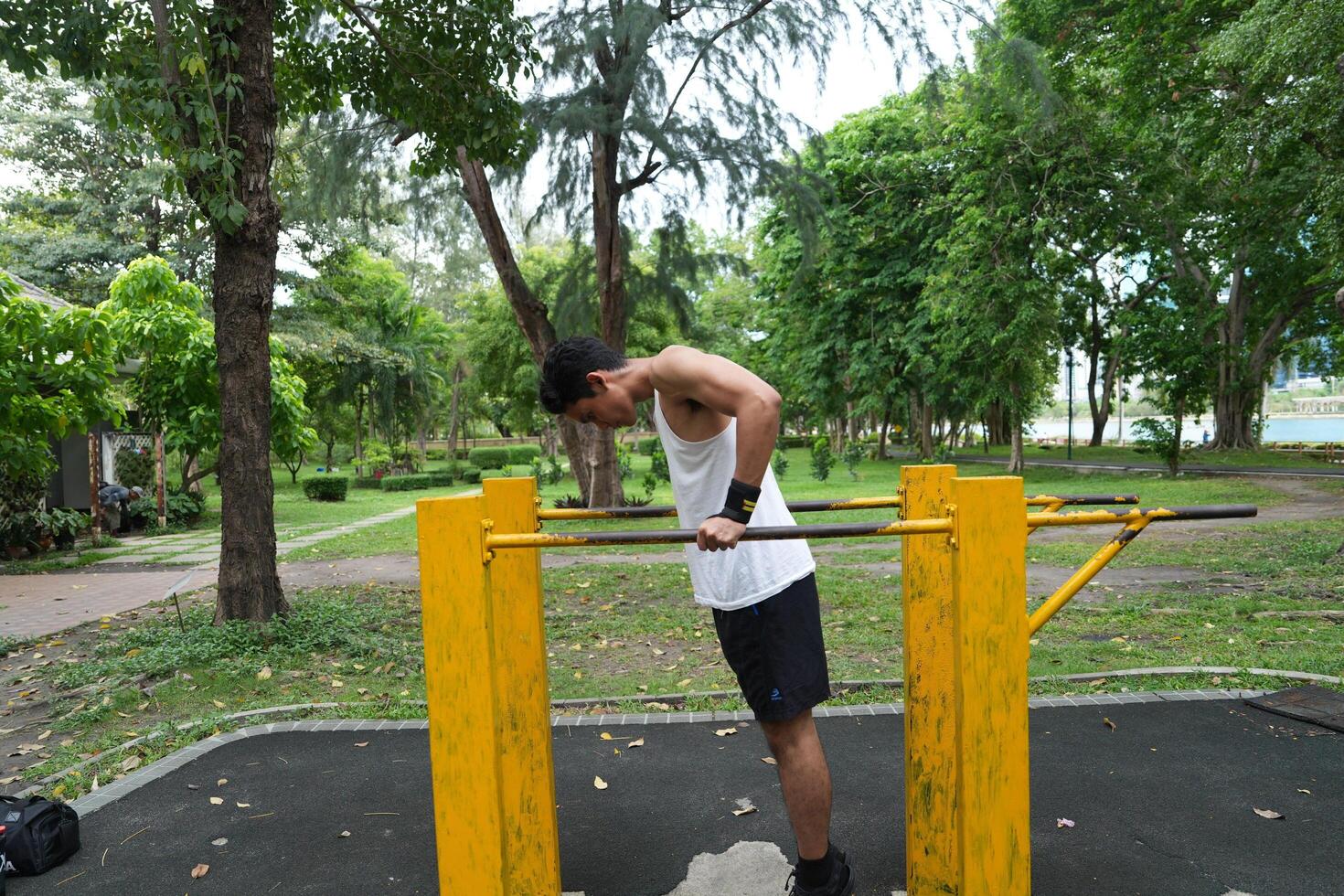 Asian man practicing gymnastics, doing gymnastics bar and hoop exercises and stretching, resting for sports. photo