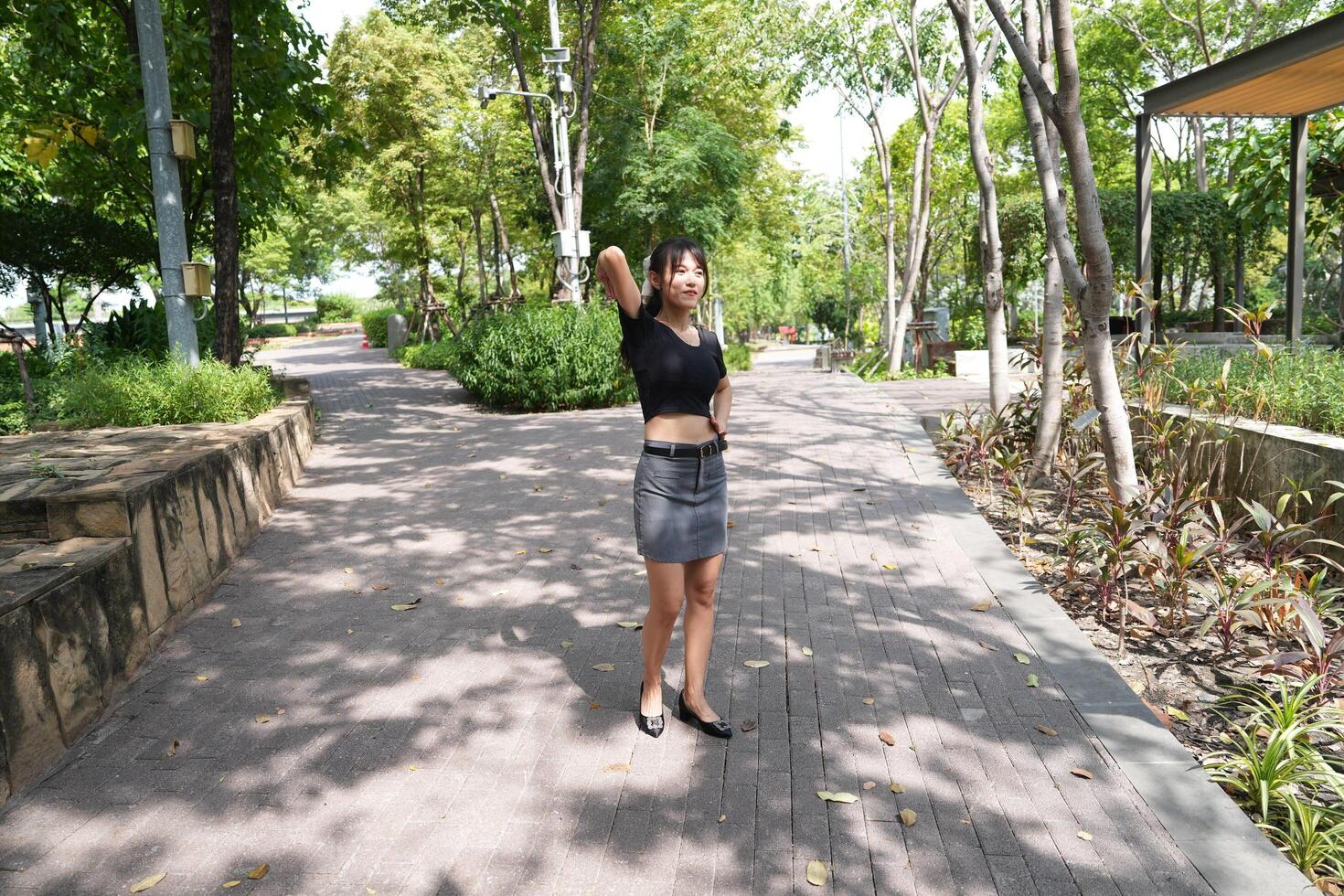 Asian woman dancing in the middle of a park photo
