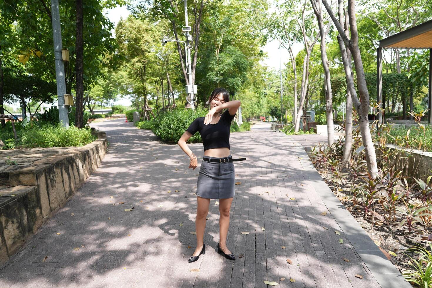Asian woman dancing in the middle of a park photo