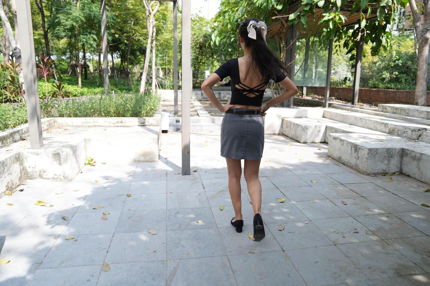 Asian woman dancing in the middle of a park photo