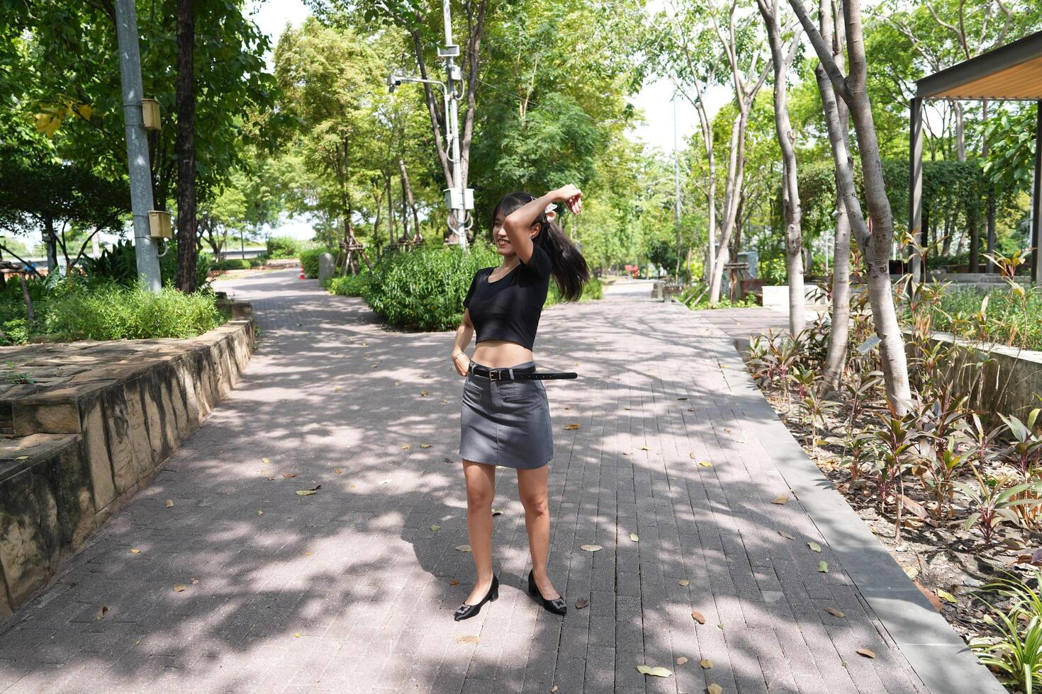 Asian woman dancing in the middle of a park photo