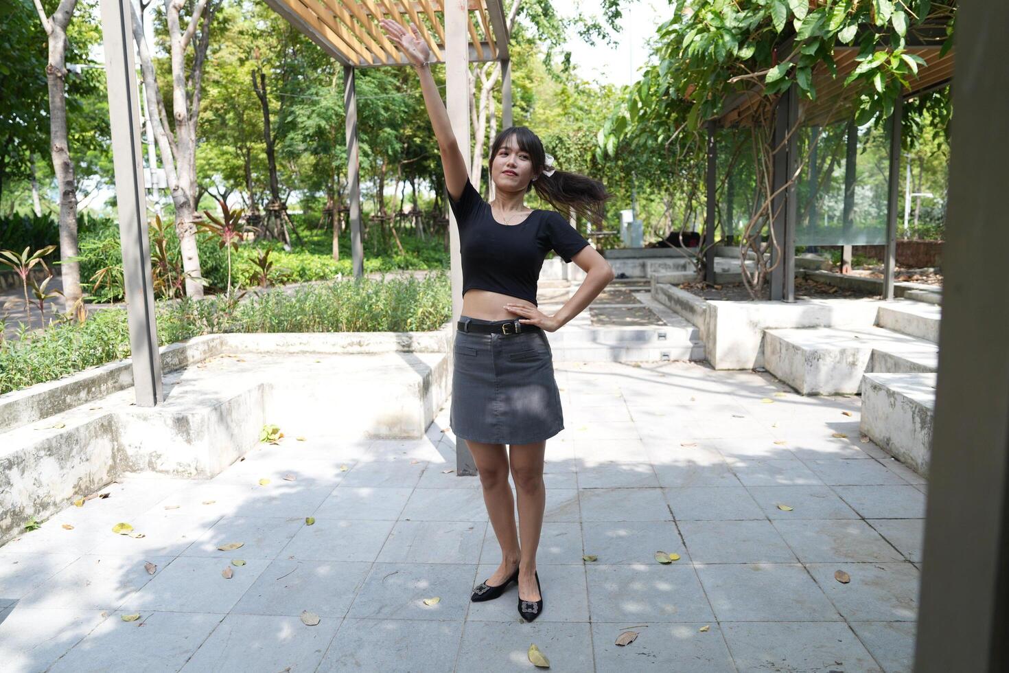 Asian woman dancing in the middle of a park photo