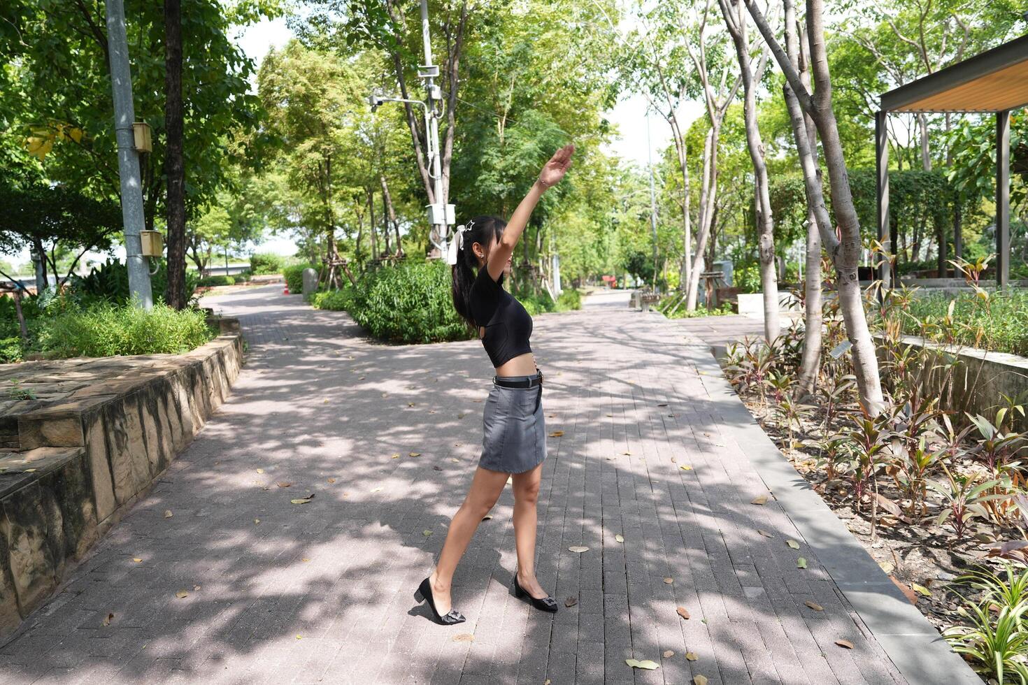 Asian woman dancing in the middle of a park photo