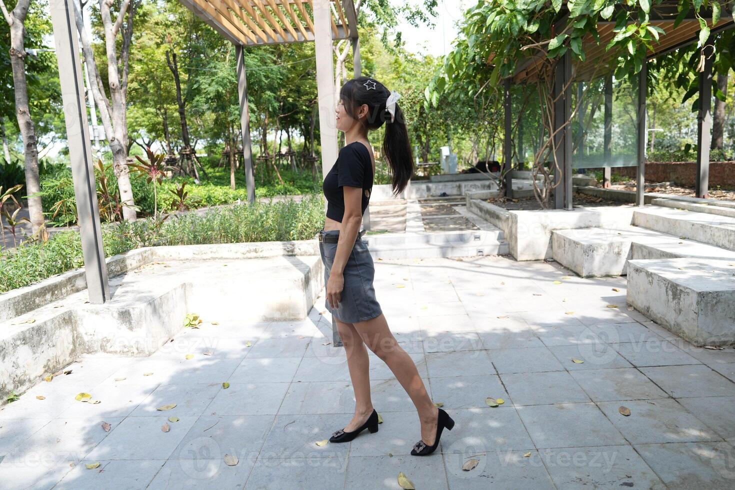 Asian woman dancing in the middle of a park photo