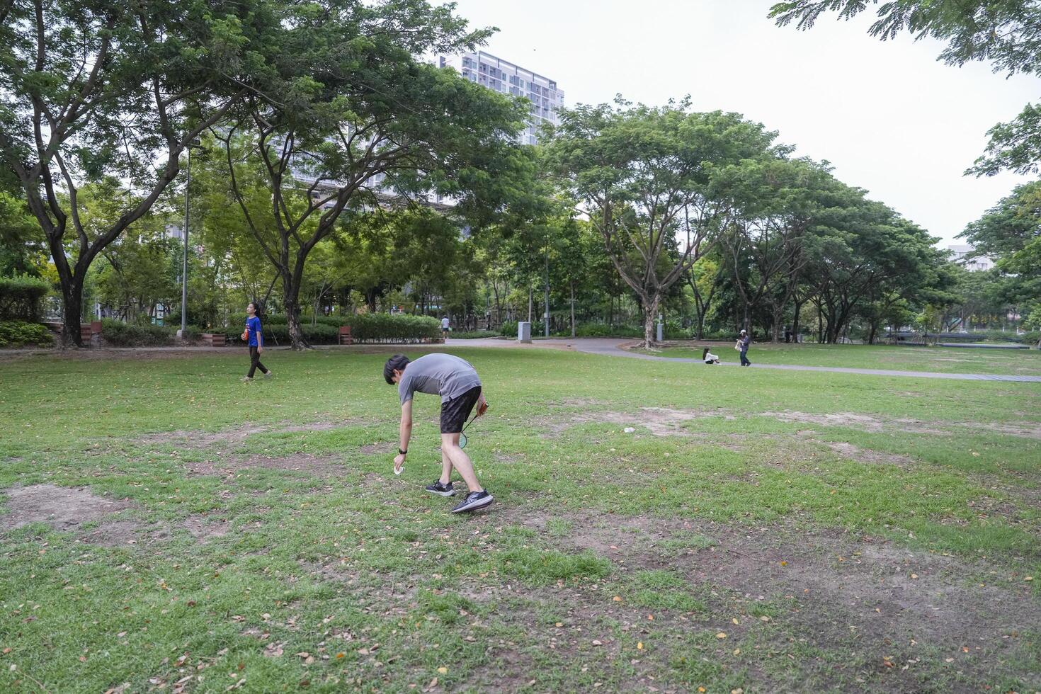 Young people play badminton and repair diligently in the park area. photo