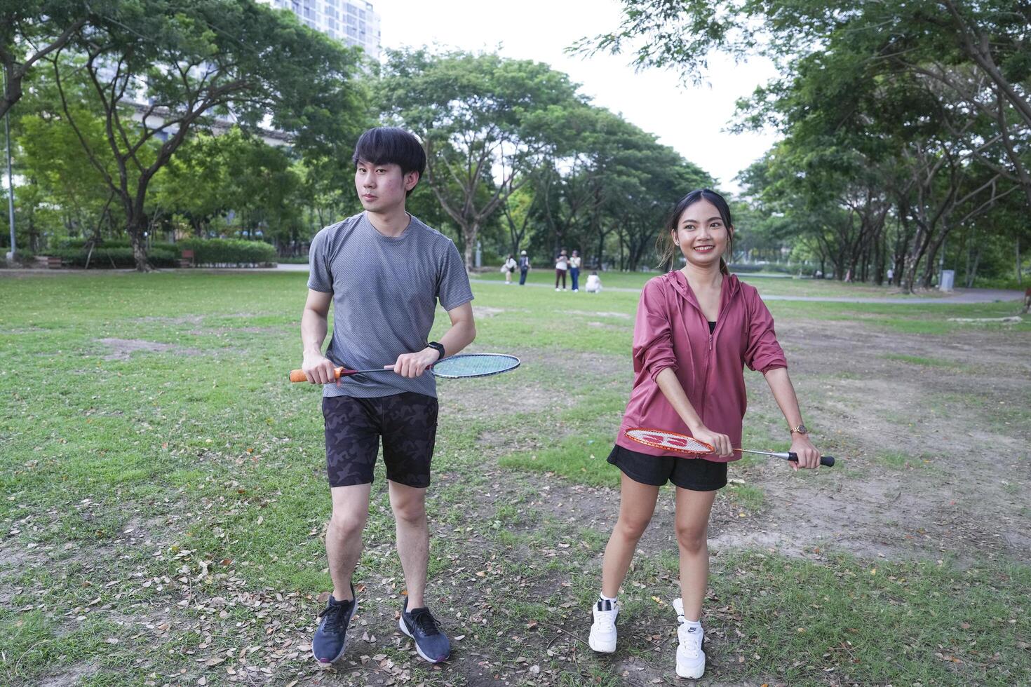 Young people play badminton and repair diligently in the park area. photo