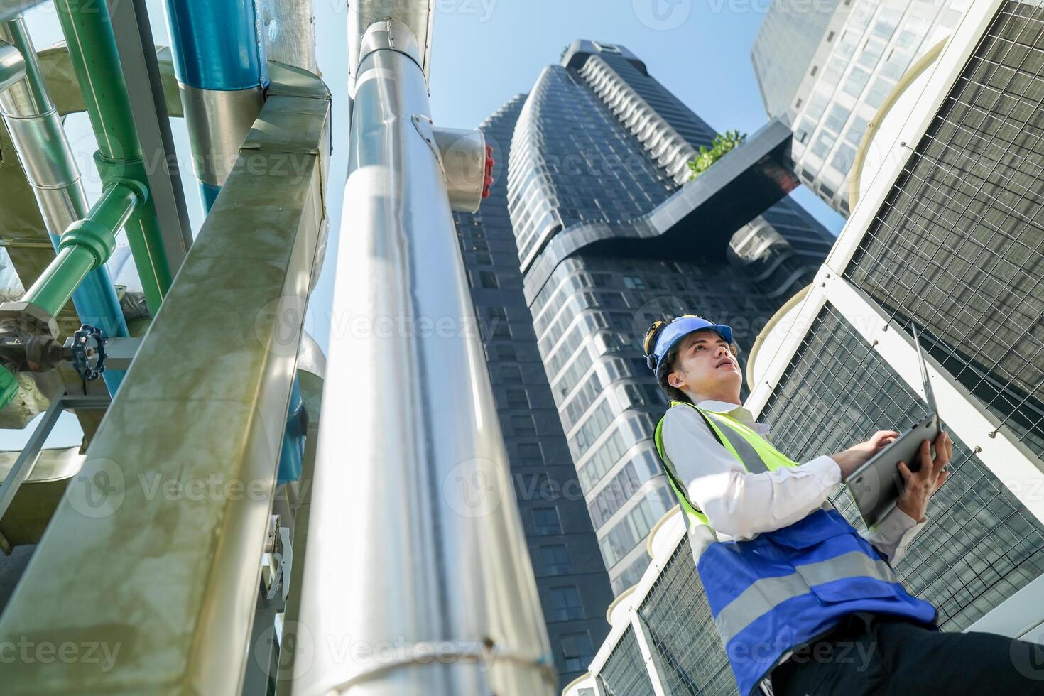 Industrial engineer adjusting pipeline valve with radio communication on construction site. Engineer on urban construction site using radio to coordinate with team on a sunny industrial rooftop. photo