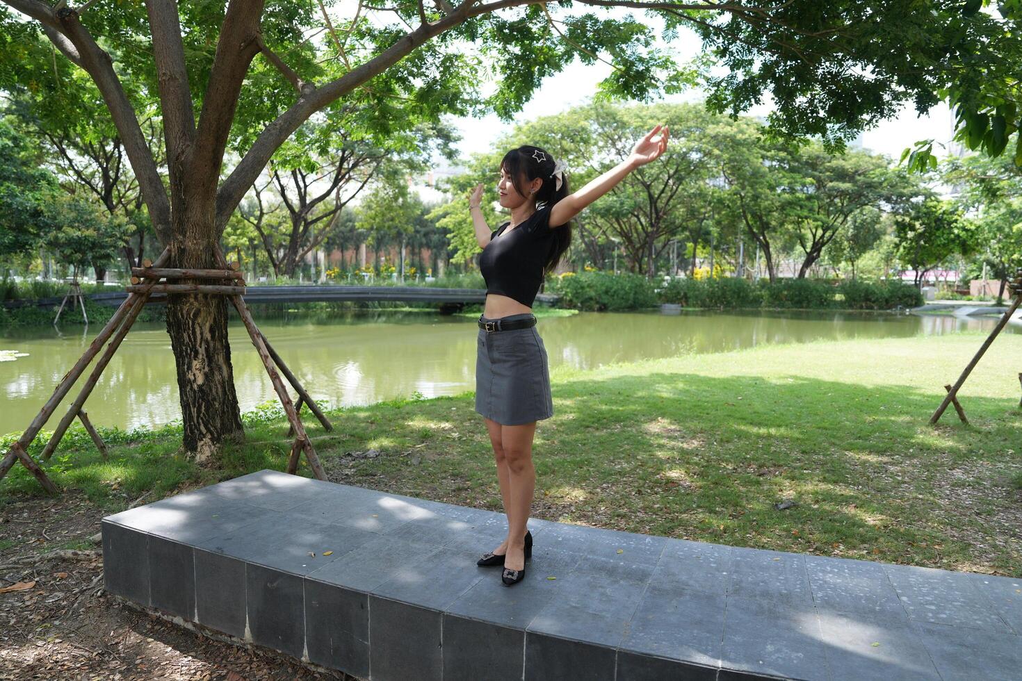 Asian woman dancing in the middle of a park photo