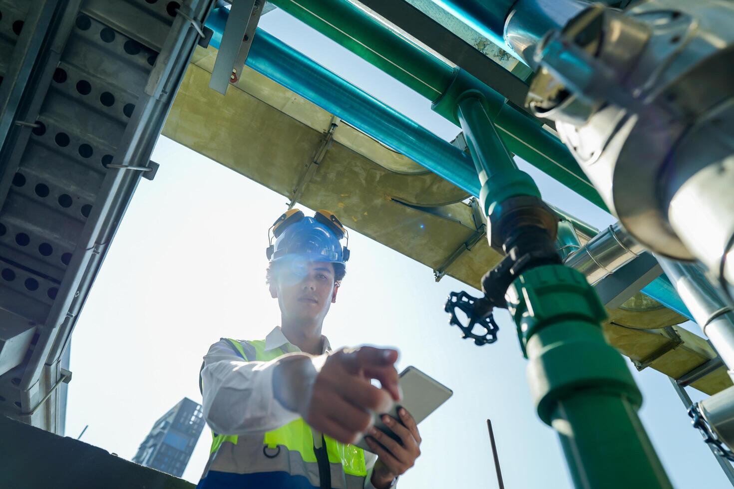 Industrial engineer adjusting pipeline valve with radio communication on construction site. Construction worker using walkie-talkie to coordinate machinery adjustments on a sunny day. photo